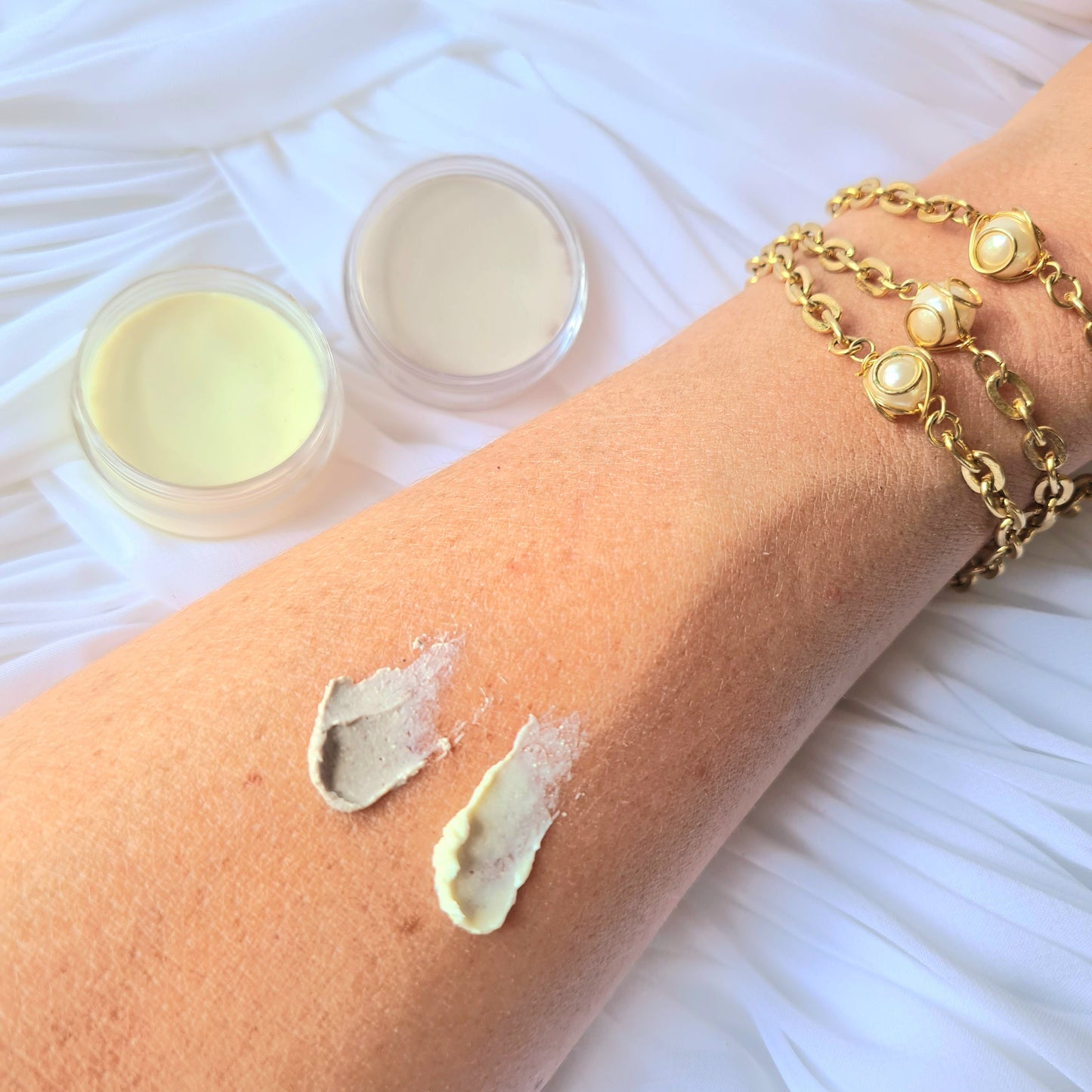 beef tallow Cream being applied to a person's arm with two containers of cream on a white textured surface.