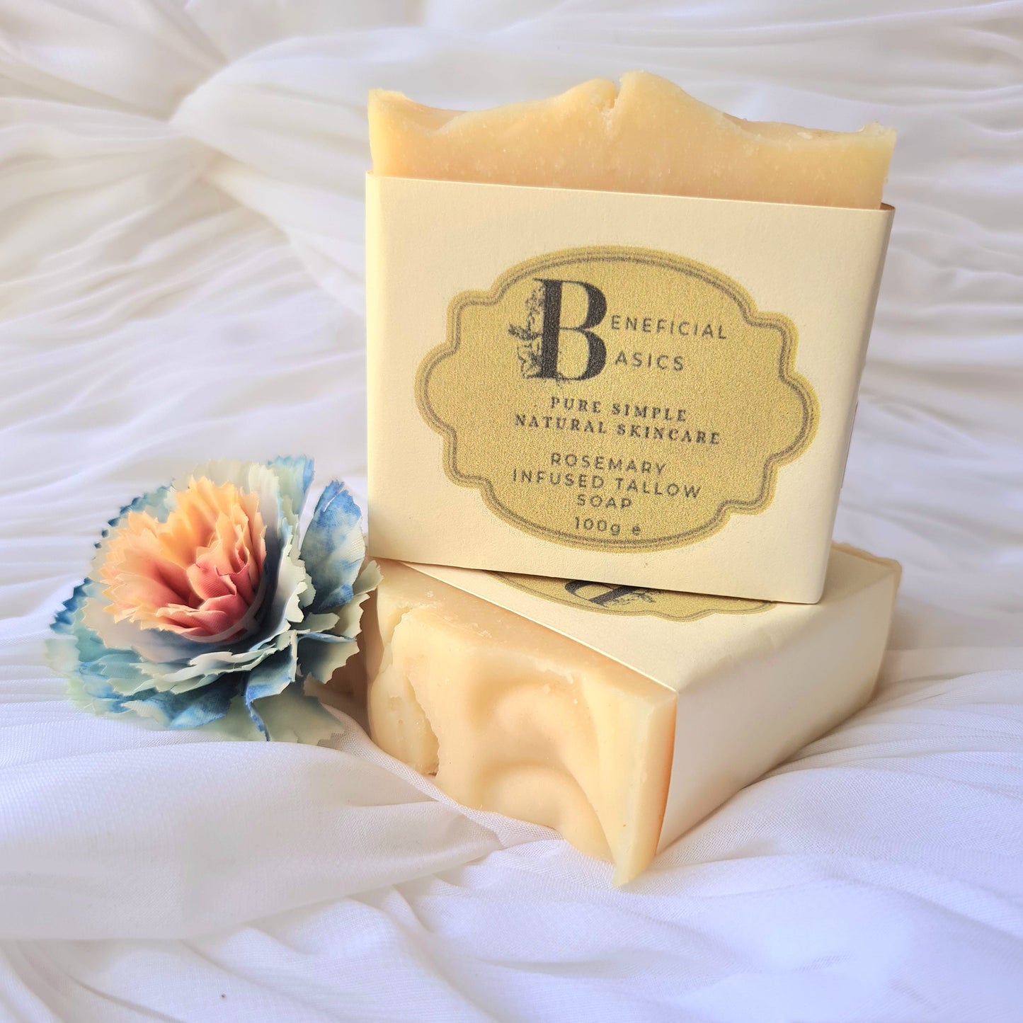 Two bars of rosemary beef tallow soap with a visible brand label on a white textured surface.