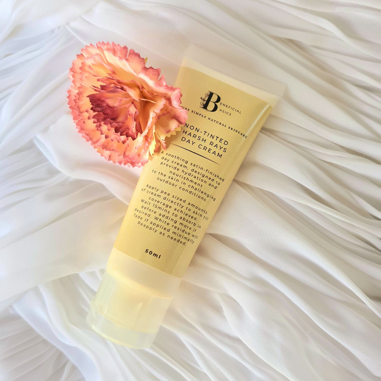 Tube of beef tallow BB cream with a pink flower on a white textured background