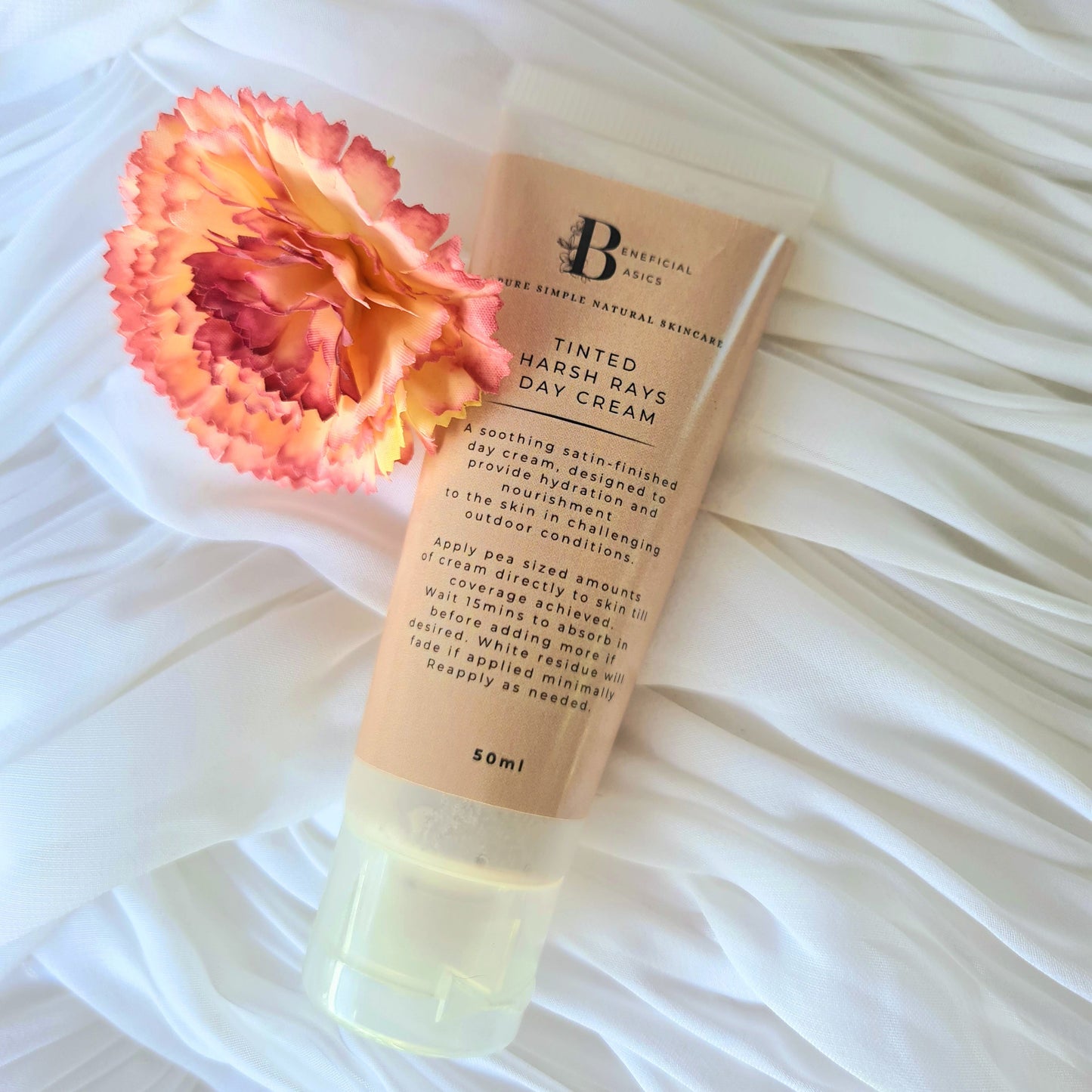 Tinted beef tallow hand and body cream with a pink flower on a white textured background