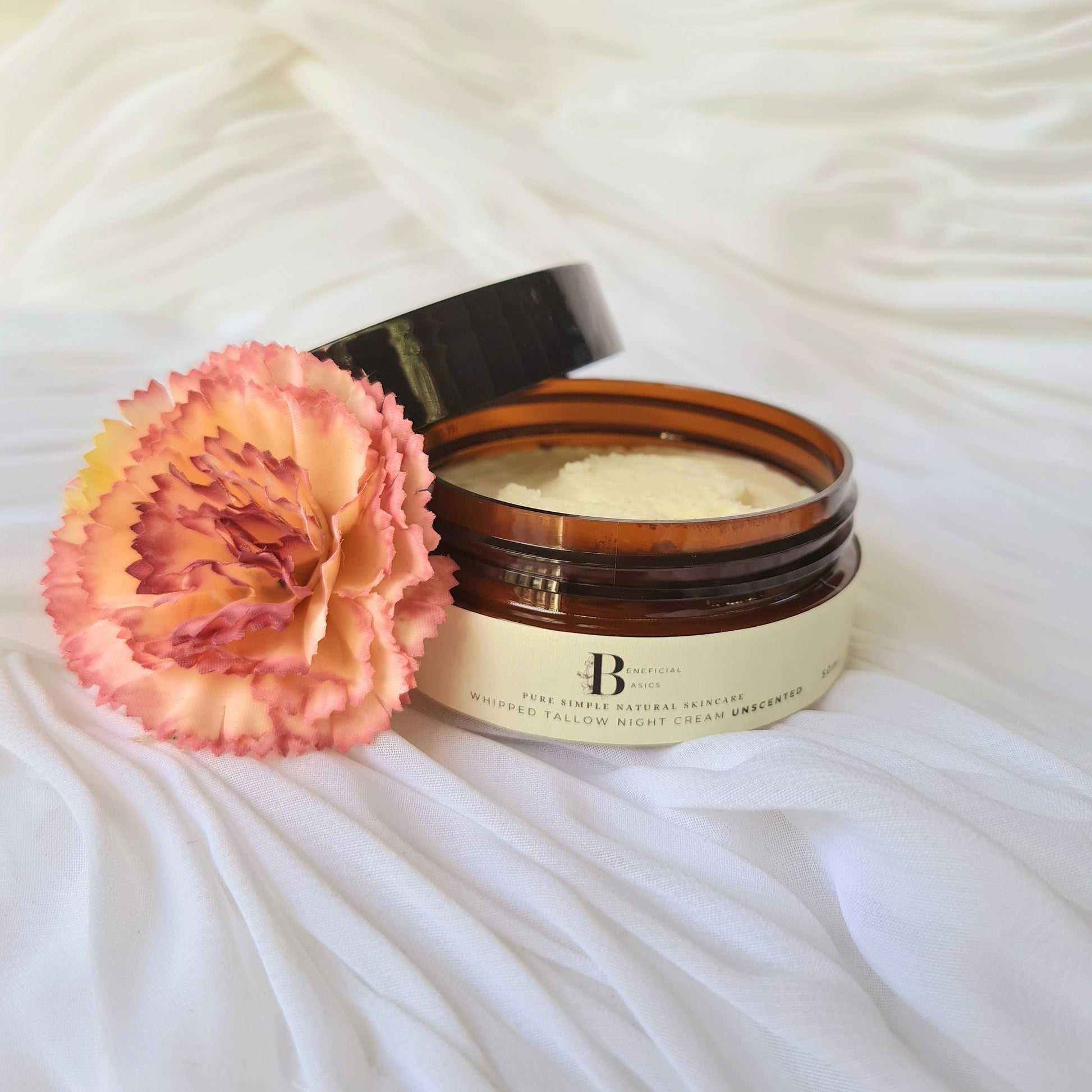 beef tallow face cream jar with a pink flower on a white textured surfacer
