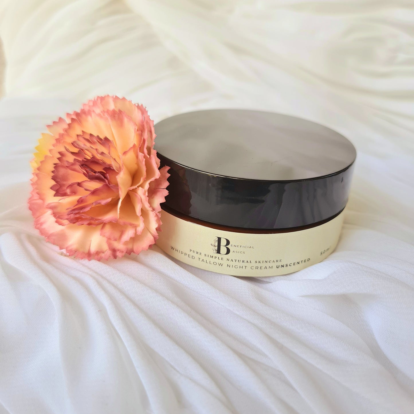 beef tallow cosmetic jar with a pink flower on a textured white surface